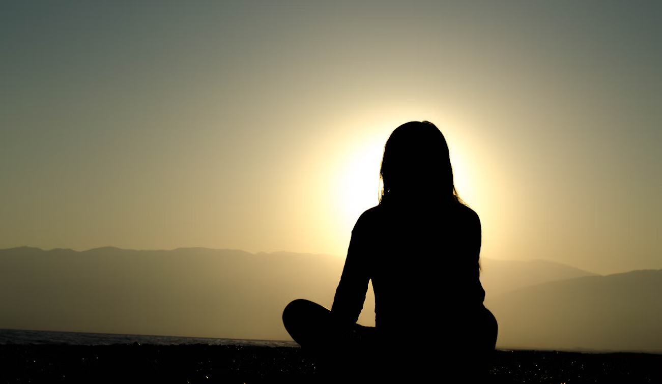 Woman meditating during sunrise